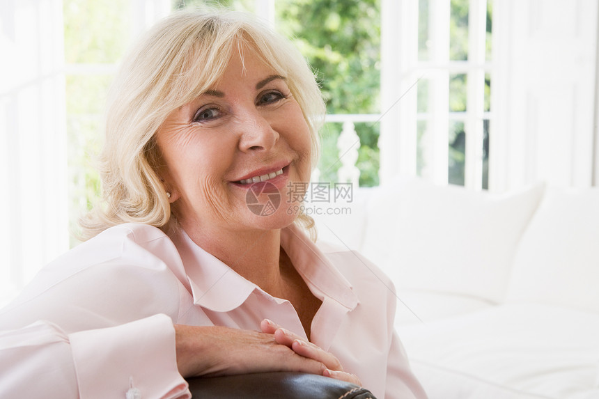 客厅中的女人微笑着女性水平沙发相机休息室长椅女士退休长度图片