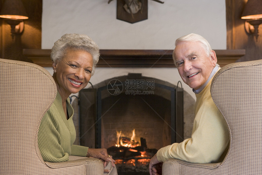 坐在起居室的一对夫妇 在壁炉边微笑女性女士丈夫扶手椅男人长度退休休息室男性客厅图片
