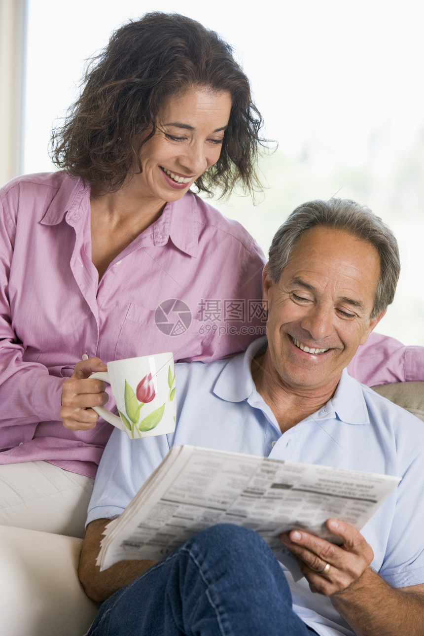 一对夫妇在报纸上笑着放松长椅阅读客厅女士咖啡男性两个人团结妻子休息室图片