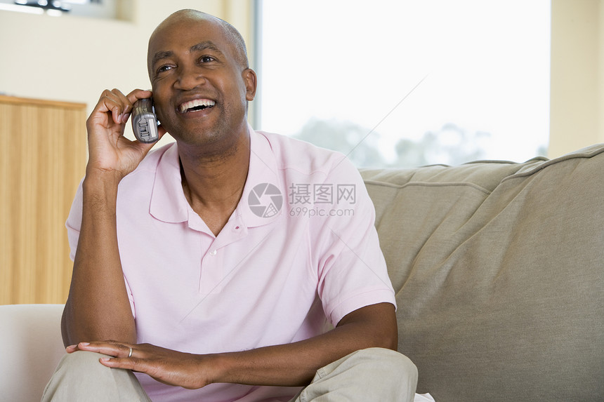 男人用电话和微笑坐在客厅里的人图片
