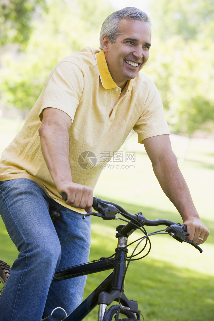男人在户外的自行车上微笑着成人活动水平享受中年长度男性公园农村骑术图片