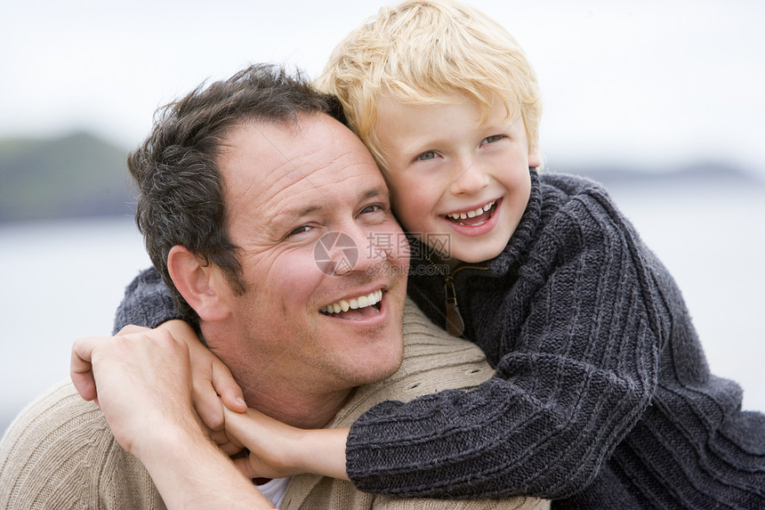 父亲和儿子在海滩上微笑男生爸爸男性季节孩子视图海岸感情拥抱衣服图片