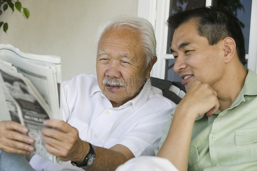 父亲和儿子一起阅读报章图片