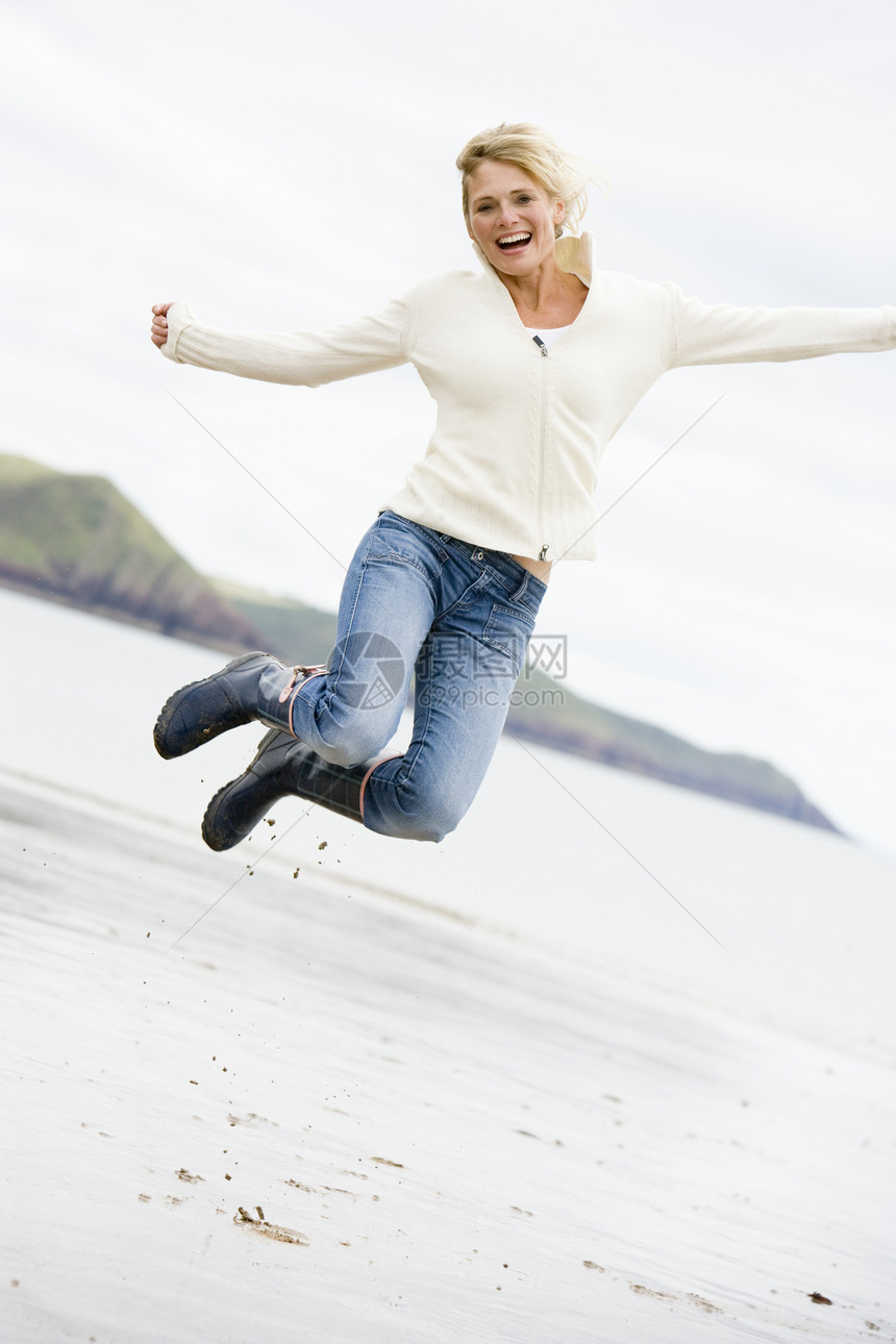 女人在海滩上欢笑的跳跃图片