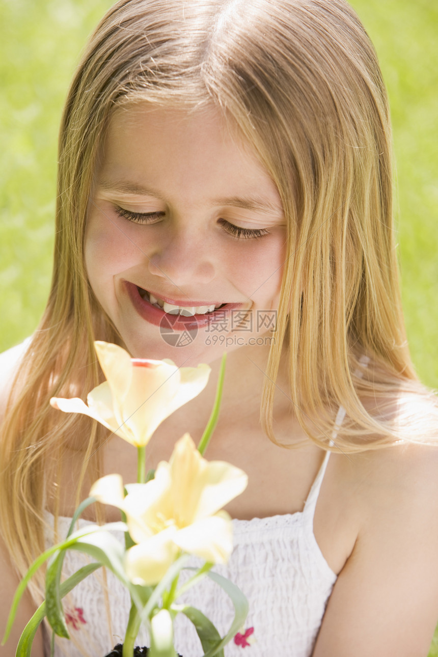 站在户外的年轻女孩带着鲜花微笑季节相机花朵植物农村公园图片