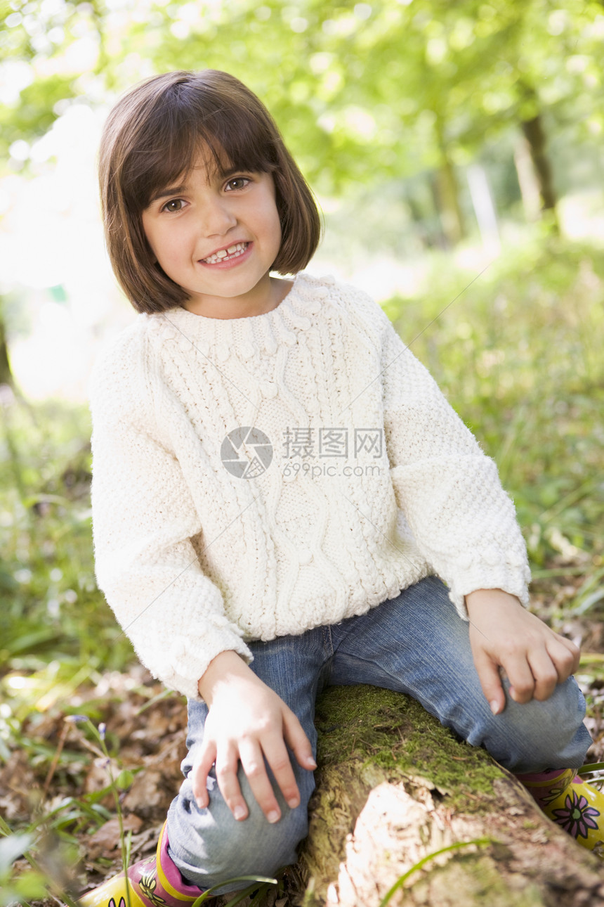 坐在树木上笑着的树林里的年轻女孩微笑林地雨靴女性公园农村森林孩子靴子孩子们图片