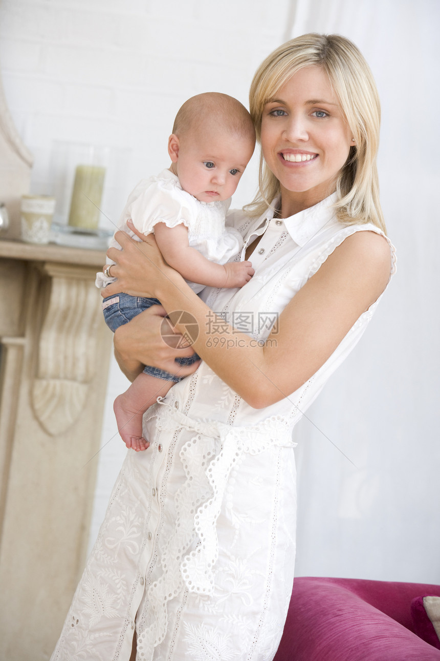 母亲在起居室抱着婴儿微笑相机水平女士女孩两个人照顾女儿拥抱家长女性图片