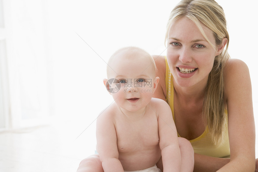 母亲和婴儿在室内微笑女士水平照顾女儿拥抱女性女孩尿布家长两个人图片