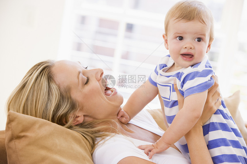 母亲在起居室抱着婴儿微笑女性家庭玩具妈妈笑声家长女孩休息室拥抱两个人图片