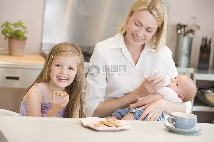 母亲在厨房喂婴儿 女儿一起吃饼干和午餐新生瓶子公式照顾女士牛奶喝咖啡兄弟奶瓶孩子图片