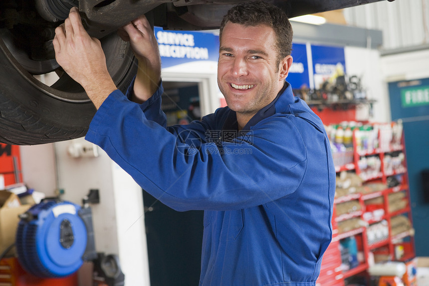 在汽车下微笑的机械工修理工成人修理机械摩托车人士车辆职业自雇图片