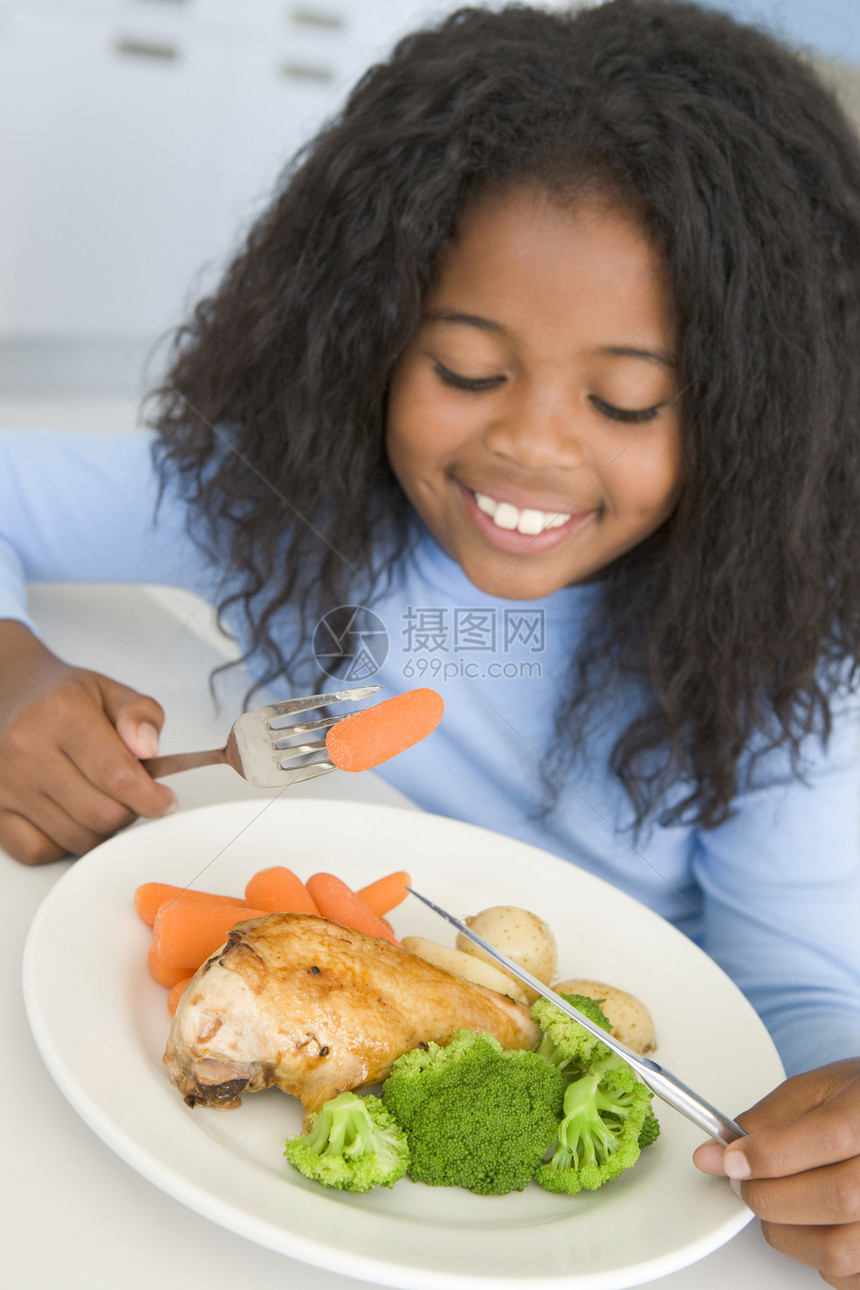 在厨房吃鸡肉和蔬菜的年轻女孩笑着吃饭食品萝卜健康饮食晚餐家禽健康孩子们儿童偏移角生产图片