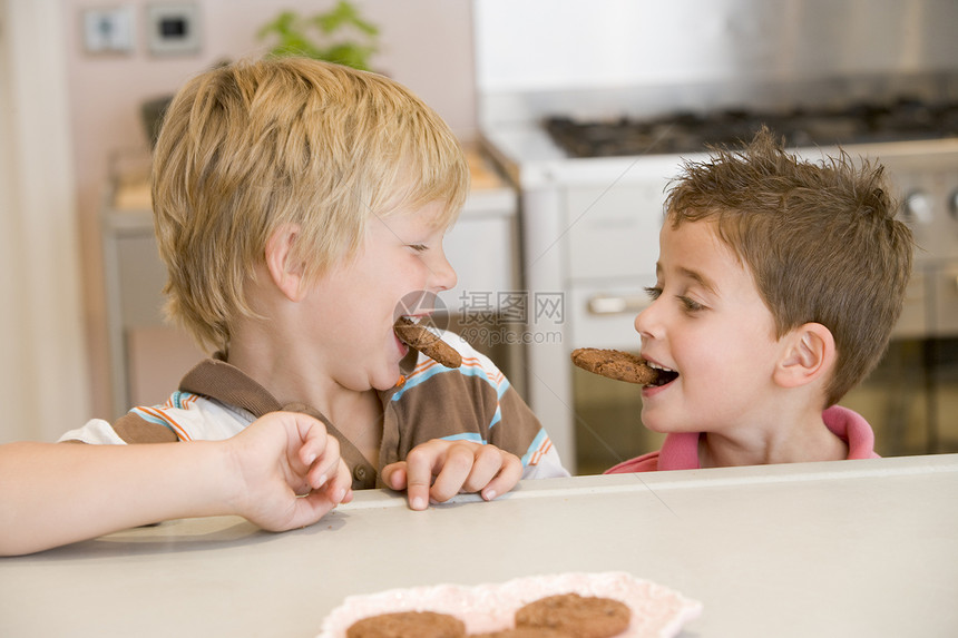 两个男孩在厨房里 笑着吃饼干图片