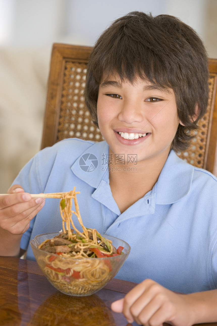 饭厅的年轻男孩在吃中国食物时微笑着笑美食儿童用具厨房刀具孩子饮食筷子男生餐具图片