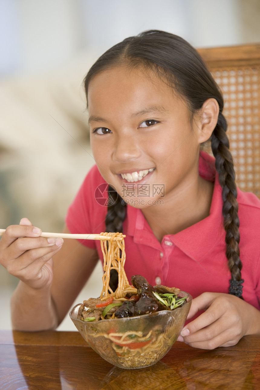 饭厅的年轻女孩在吃中国食物时微笑着笑中餐美食一个女孩孩子们刀具儿童食品用具餐具混血儿图片