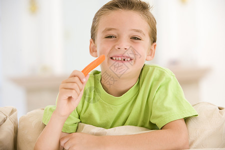 小男孩在客厅里吃胡萝卜棒 微笑着笑着高清图片