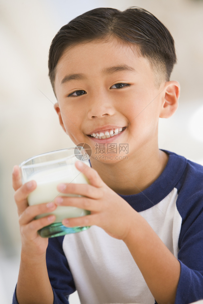 在室内喝着微笑的牛奶的年轻男孩孩子们玻璃食物奶制品享受一个男孩混血儿食品儿童孩子图片