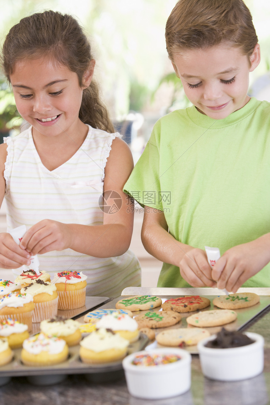 两个孩子在厨房装饰饼干 笑着小吃小男孩友谊两个人甜点享受儿童装潢蛋糕台面图片