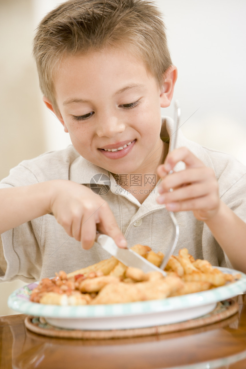 室内小男孩在吃鱼和薯片时微笑孩子们一个男孩海鲜儿童食品孩子薯条混血儿享受饭厅图片