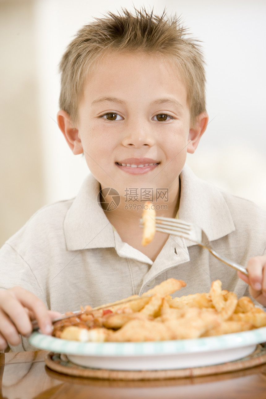 室内小男孩在吃鱼和薯片时微笑孩子们鱼片儿童一个男孩混血儿食物饮食食品饭厅海鲜图片