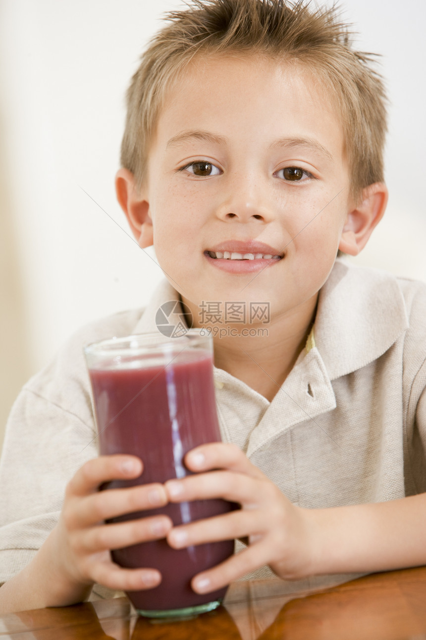 室内小男孩在喝果汁时微笑图片