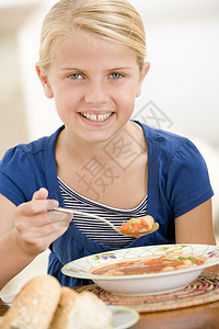 室内年轻女孩在喝汤时笑着微笑背景图片