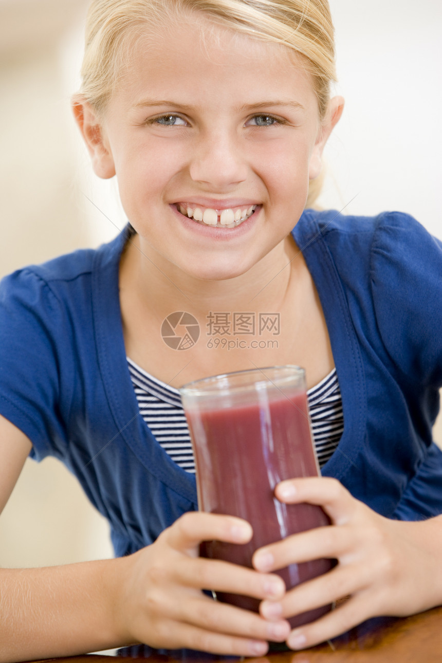 在室内喝果汁时微笑的年轻女孩图片