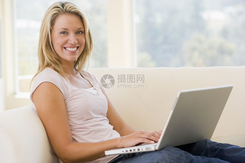 使用手持笔记本电脑微笑的客厅妇女互联网成人长度上网相机中年家庭技术女性水平图片