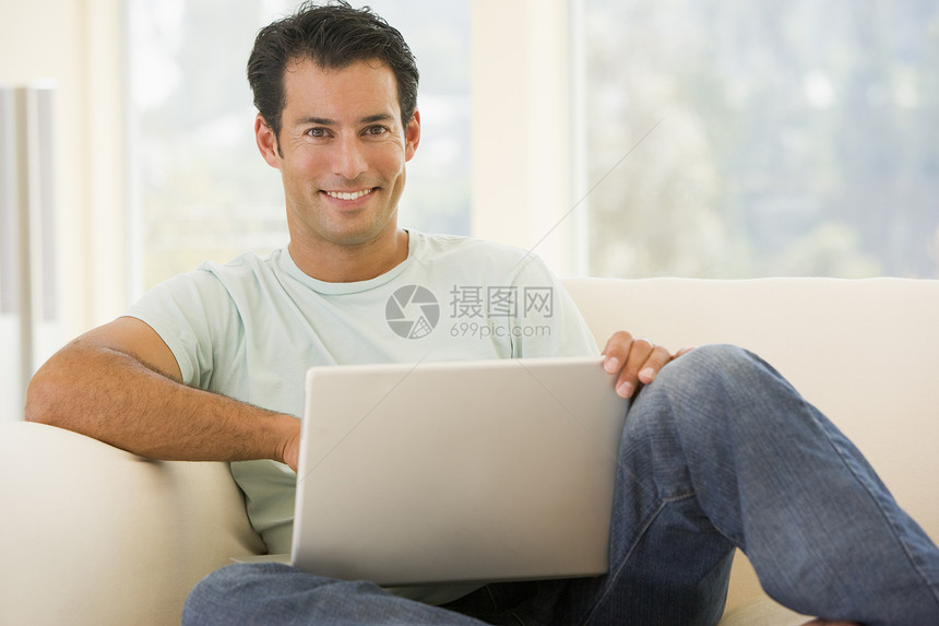 使用手持笔记本电脑笑着在客厅的人上网家庭成人互联网微笑中年男性技术长度世代图片