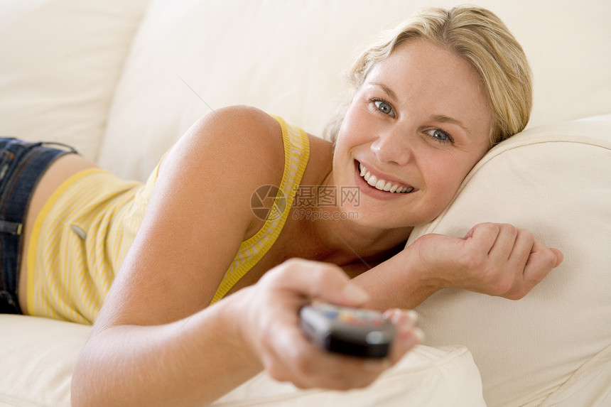 坐在客厅中 手持遥控器微笑着的女子水平女性家庭男人频道遥控电视技术成人图片