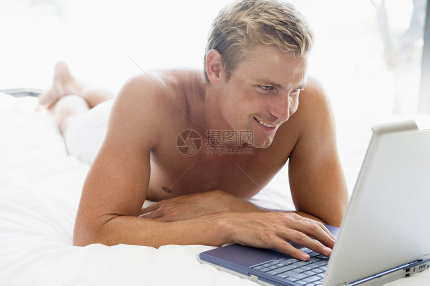 男人躺在床上 带着笔记本电脑微笑上网男性卧室中年技术双人床成人互联网水平世代图片