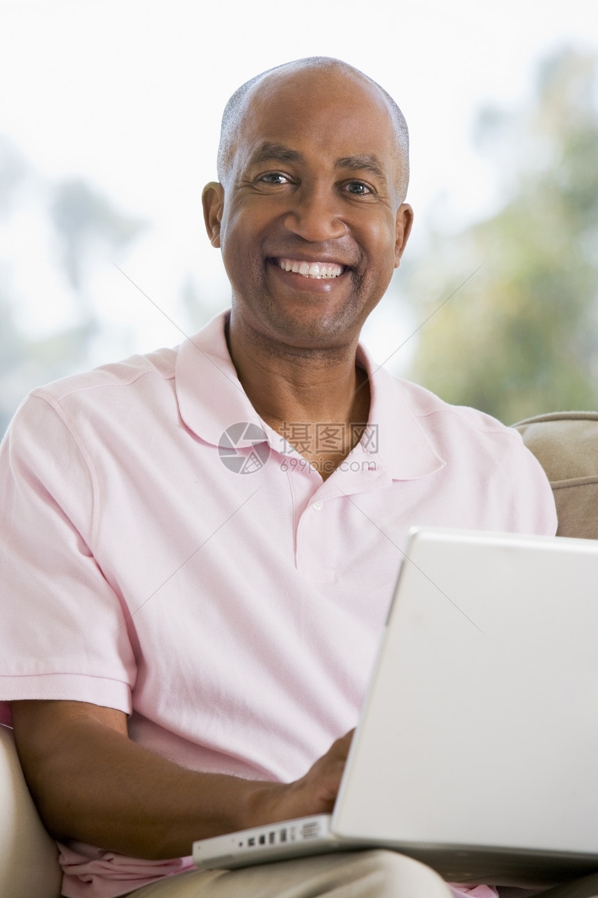 使用笔记本电脑和微笑在客厅里的人互联网沙发家庭长度相机上网技术成人中年男性图片