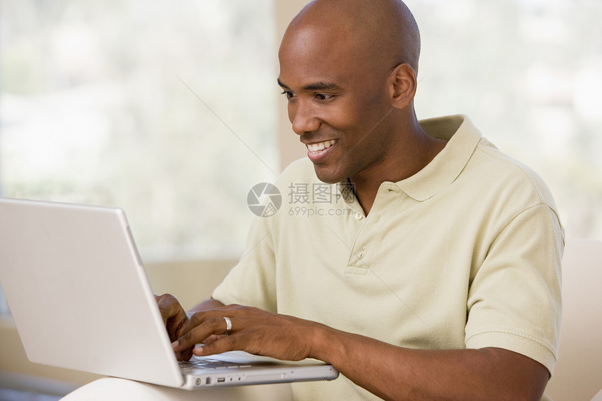 使用笔记本电脑和微笑在客厅里的人中年技术互联网长度男性成人家庭上网水平世代图片