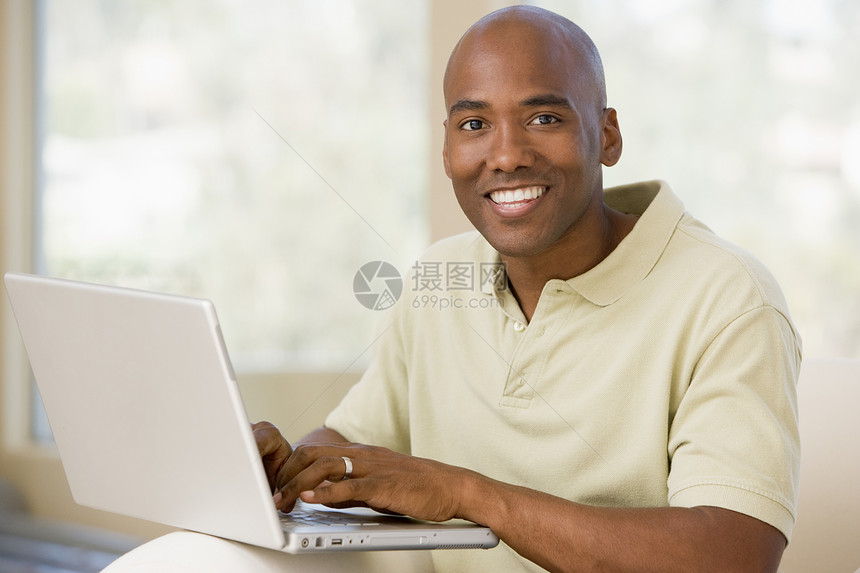 使用笔记本电脑和微笑在客厅里的人男性上网长度成人中年世代家庭技术互联网相机图片