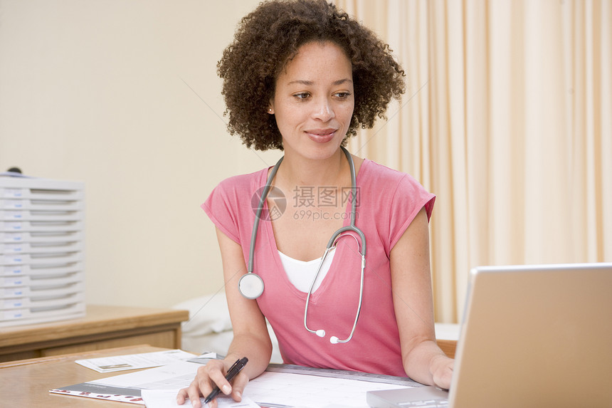 在医生办公室使用笔记本电脑的医生微笑全科病历休闲笔记工作女士外科保健疾病着装图片
