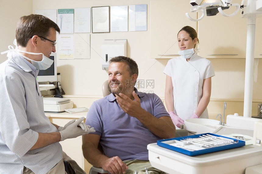 考试室的牙医和助理 坐在椅子上的男人微笑着笑着在检查室里图片