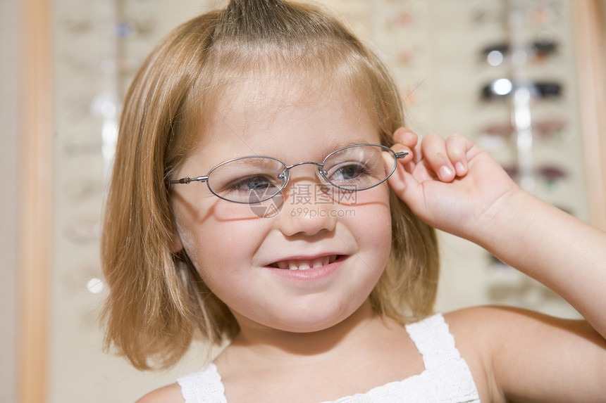 年轻女孩在观察家的眼镜上试着微笑框架店铺配镜师顾客女性保健水平验光师卫生商业图片