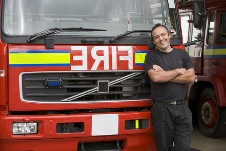 一名消防员站在消防机旁边的肖像男人英雄中年人好榜样服务消防男性水平情况消防队员背景图片
