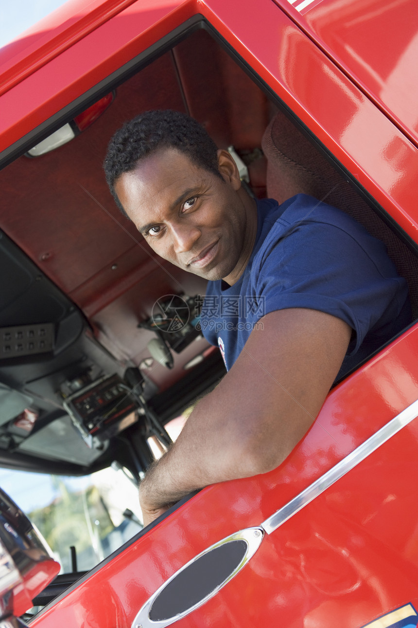 一名消防员坐在一辆消防车的出租车上男人微笑中年消防服务好榜样消防队员情况司机英雄图片