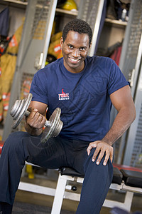 在消防站更衣室对消防员的肖像储物柜锻炼消防队员消防体型举重男人消防服微笑制服背景图片