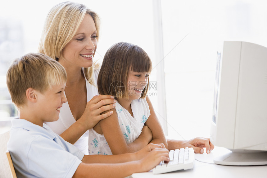 妇女和两个孩子在家中办公室 带有电脑微笑的女婴和两个幼童图片