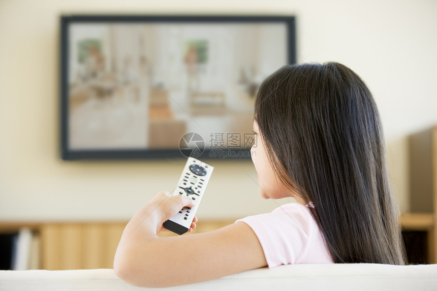 住在客厅的年轻女孩 带平板屏幕电视和远程电视图片
