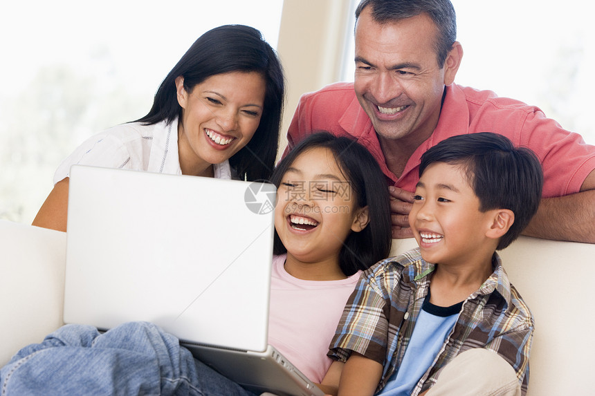 家庭在起居室 膝上型电脑微笑母亲孩子们冲浪男生家长中年男人女士父母混血图片