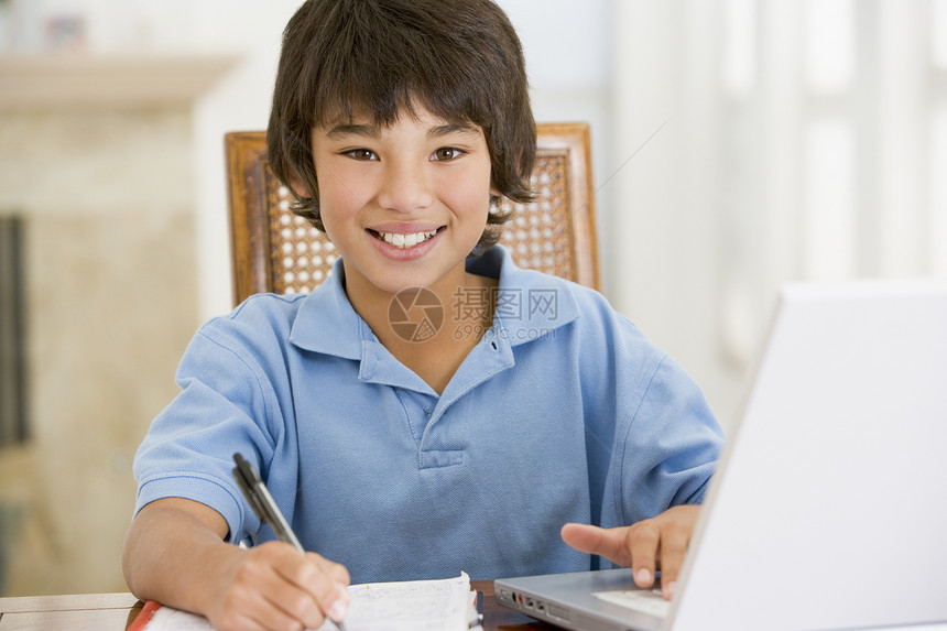 带着笔记本电脑的男孩在餐厅做家庭作业 微笑着孩子们客厅写作技术桌子冲浪孩子家庭作业小男孩水平图片