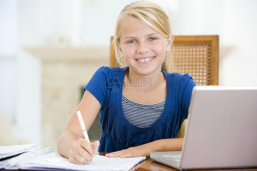 带笔记本电脑的年轻女孩在餐厅做家庭作业时微笑着笑图片