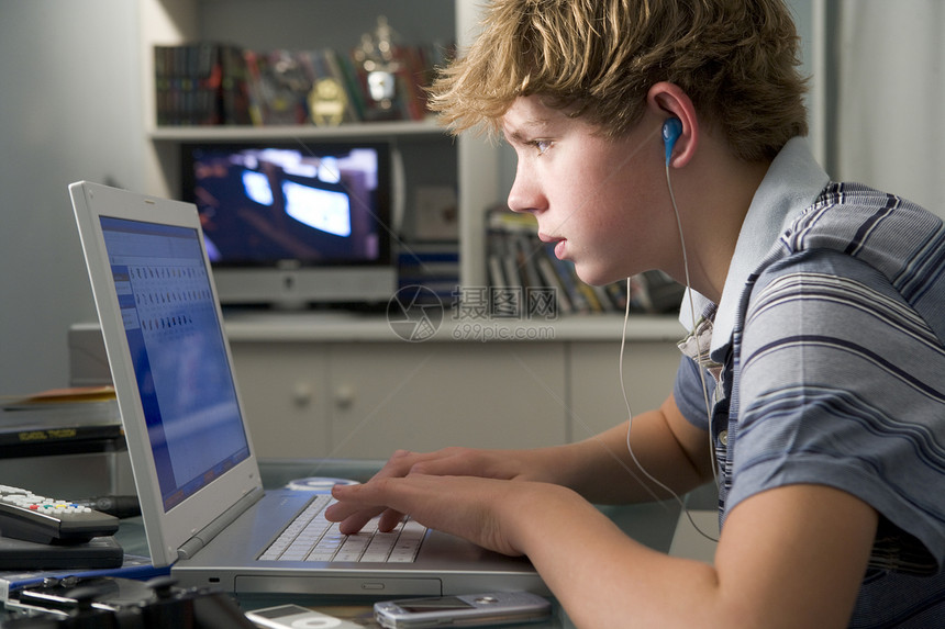 利用笔记本电脑和听MP3播放器在卧室的年轻男孩控制器时间青年音乐就寝游戏机孩子孩子们电脑游戏技术图片