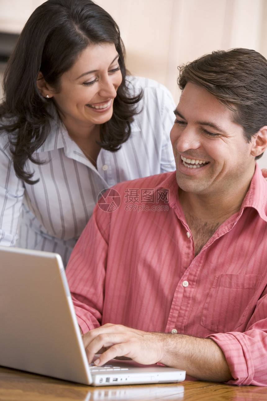 厨房中的夫妇 用笔记本电脑微笑图片