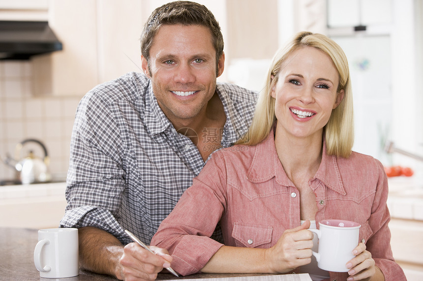 在厨房的一对夫妇 报纸和咖啡笑着两个人丈夫女性一杯茶阅读柜台男性热饮中年妻子图片