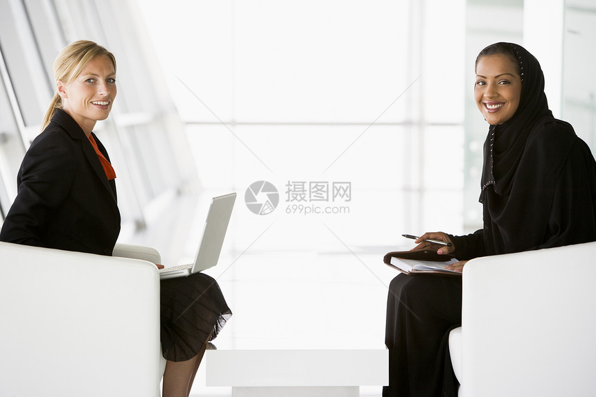 两个在室内的商务人士 带着笔记本电脑说话和微笑女性幸福人士大堂商业同事衣服男性情感洗碗机图片