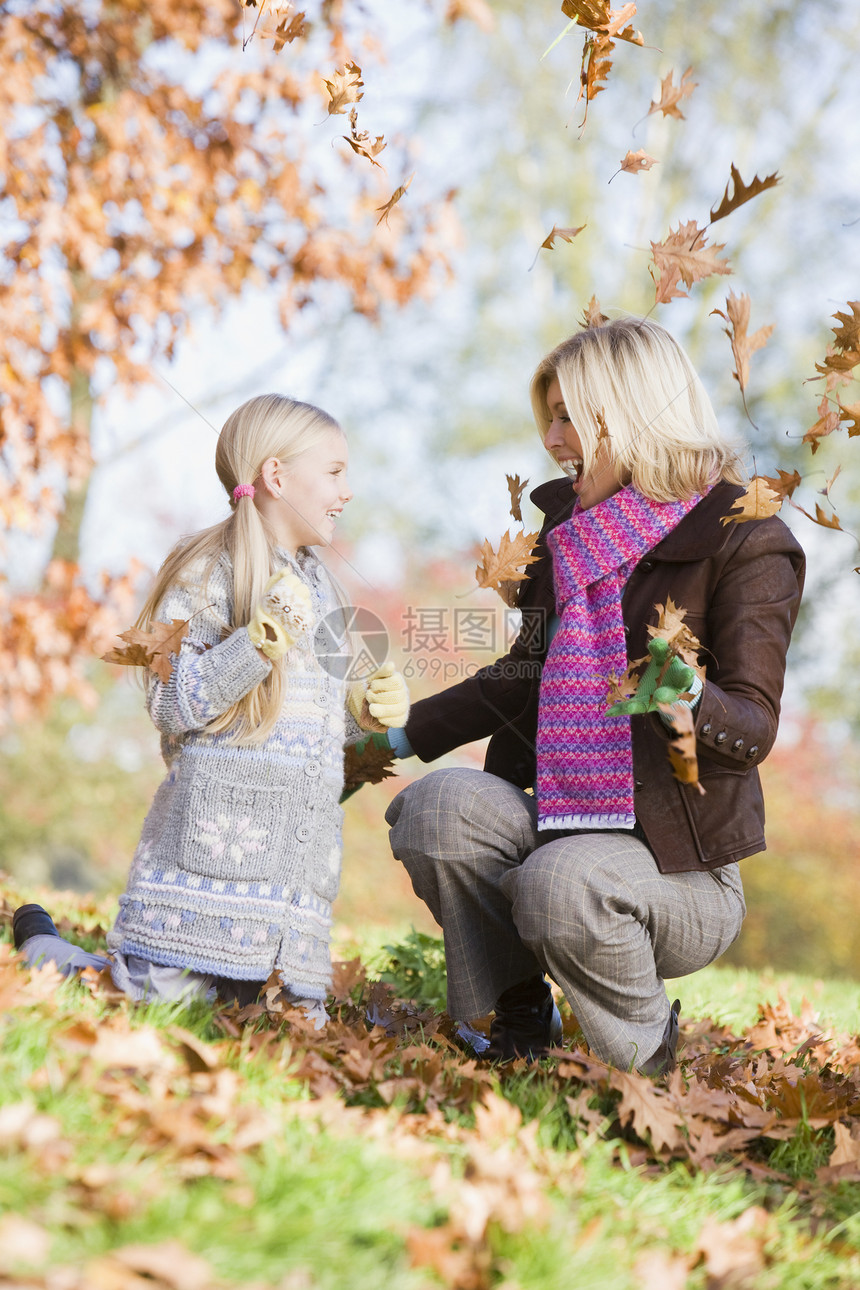在公园户外露天玩叶子和微笑的女子和少女焦距小学生成年人人种阶段母亲花园女性家庭小学图片